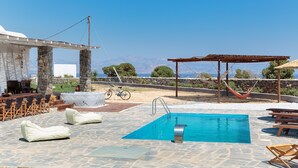 A pool area with lounge chairs, a hot tub, and a pergola overlooking a scenic view. - Charming little villa Elena with private pool and sea views! (Paros)