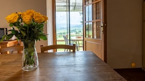 Una mesa de madera con un florero de vidrio transparente que contiene rosas amarillas.