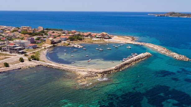 An aerial view of a coastal town with clear blue waters, a marina with boats, and a mix of residential and commercial buildings. - Comfy nest in a garden, 1,5km to the sandy beach (Marathopoli)