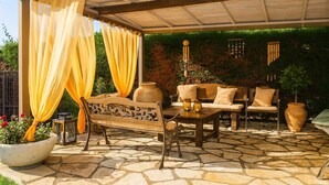 An outdoor patio with a stone floor, a wooden bench, a table, and chairs. - Comfy nest in a garden, 1,5km to the sandy beach (Marathopoli)