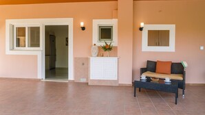 A spacious room with a sliding glass door leading to a kitchen, a white cabinet with a mirror above it, and a wicker sofa with cushions. - Comfy nest in a garden, 1,5km to the sandy beach (Marathopoli)