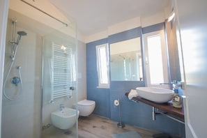 A modern bathroom with a glass shower enclosure, a white sink, and a large mirror.