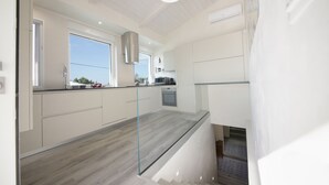 A modern kitchen with a glass backsplash, stainless steel appliances, and a large window providing natural light. - Villa Cavuzzi (Polignano a Mare)