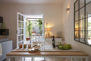 A dining area with a table set for two, a bottle of wine, and a bowl of grapes. - Casa dei Nespoli (Monopoli)