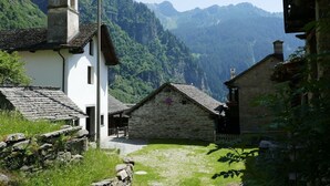 Un bâtiment traditionnel en pierre, doté d’un clocher, entouré de montagnes verdoyantes.
