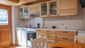 Une cuisine dotée de meubles en bois, d’une cuisinière, d’un évier et d’un coin repas avec une table et des chaises.