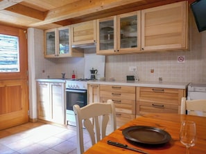 Eine Küche mit Holzschränken, einem Herd, einer Spüle und einem Essbereich mit Tisch und Stühlen.
