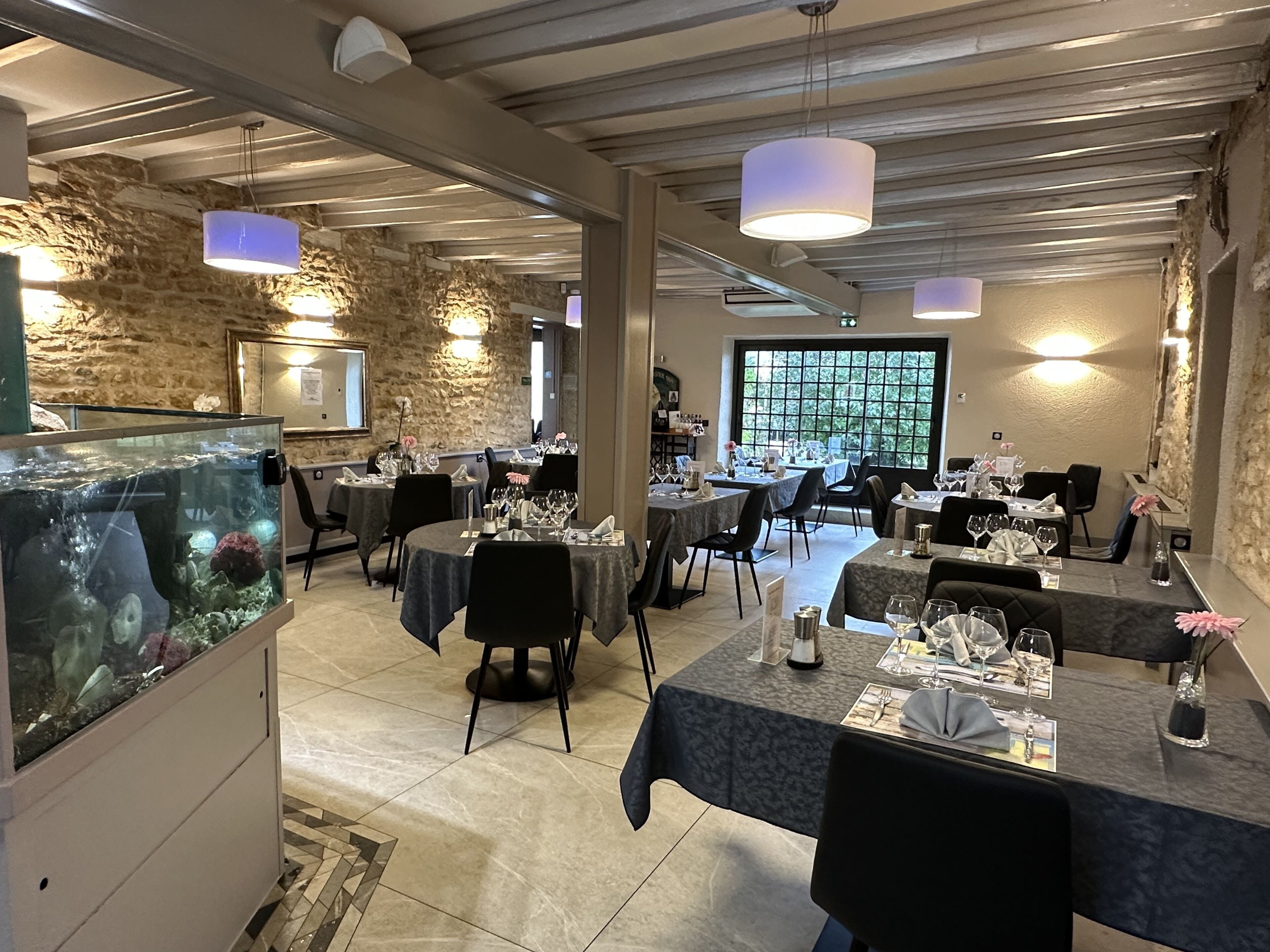 Een restaurant met stenen muren, gedekte tafels en hangende pendantlampen.
