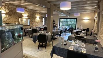 Een restaurant met stenen muren, gedekte tafels en hangende pendantlampen.