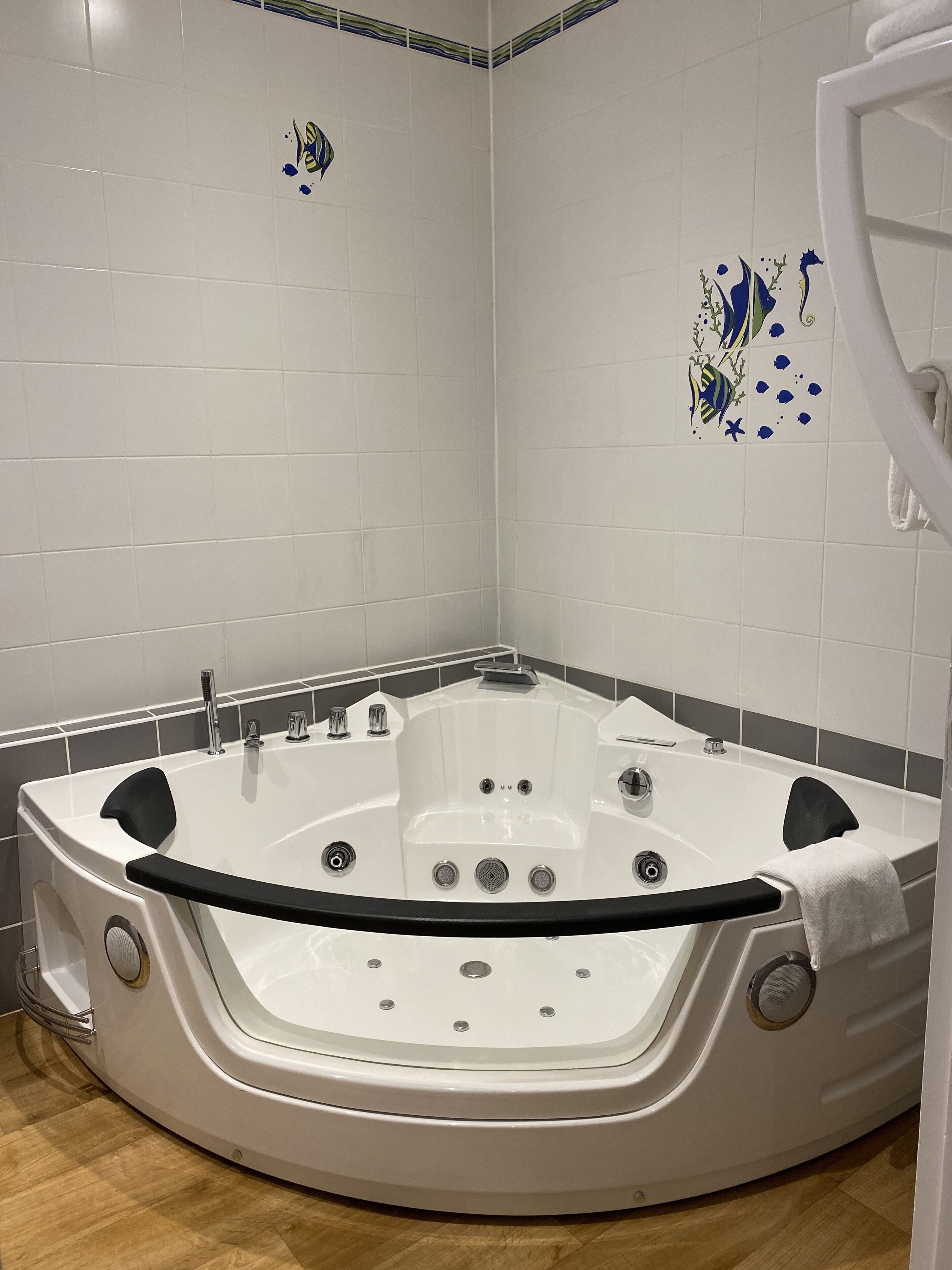 Une salle de bain moderne avec une baignoire sur pieds, des murs carrelés et un plancher en bois.