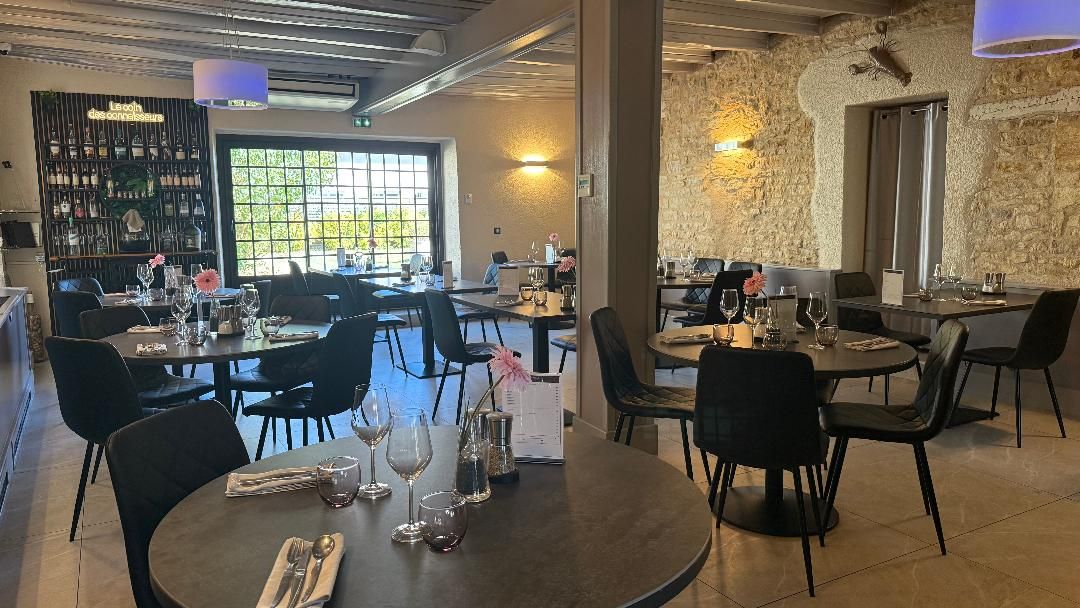 A restaurant with multiple tables and chairs, a wine rack, and a view through a large window.