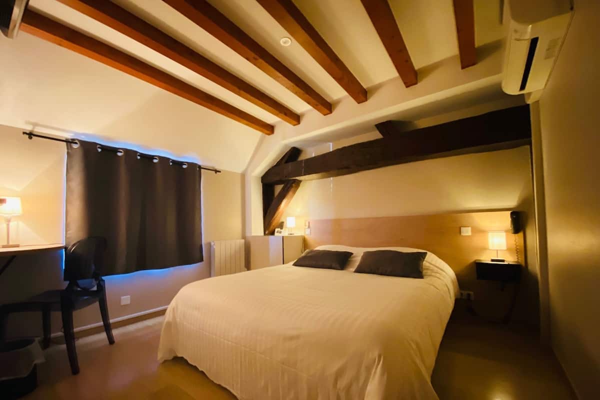 A bedroom with a large bed, a desk, and a chair.