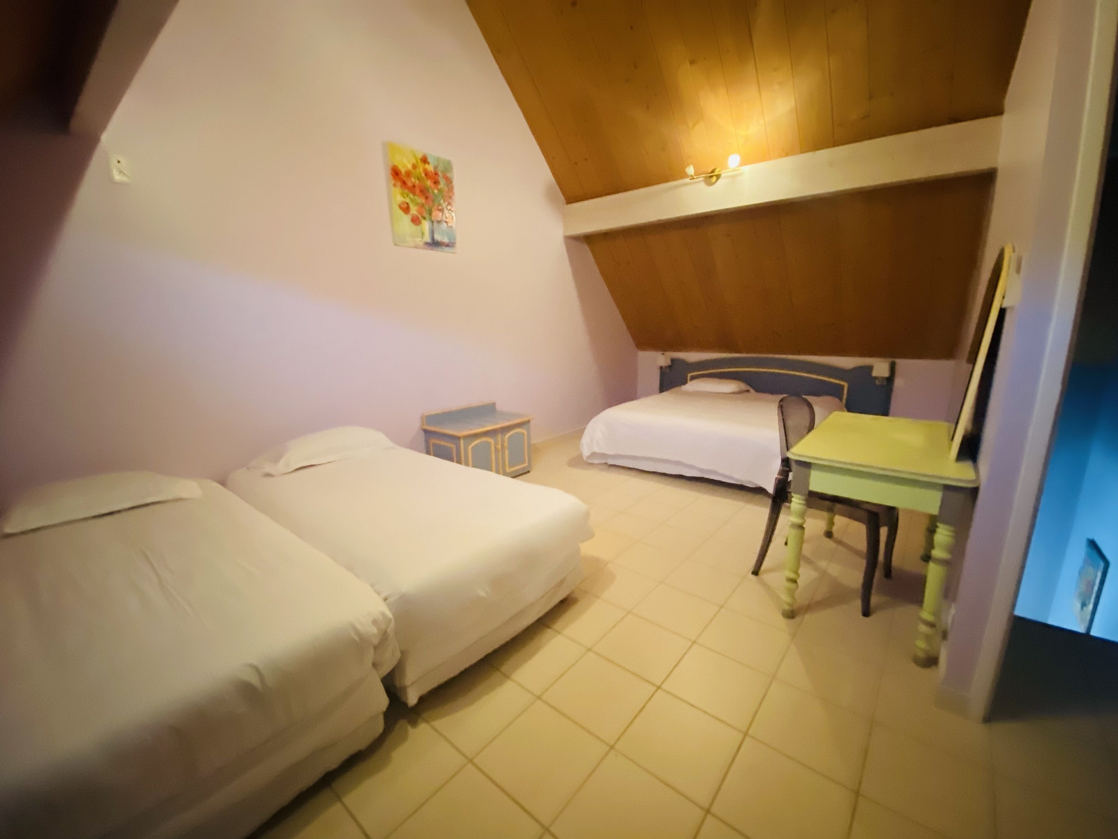 A small, cozy room with two beds, a desk, and a chair.