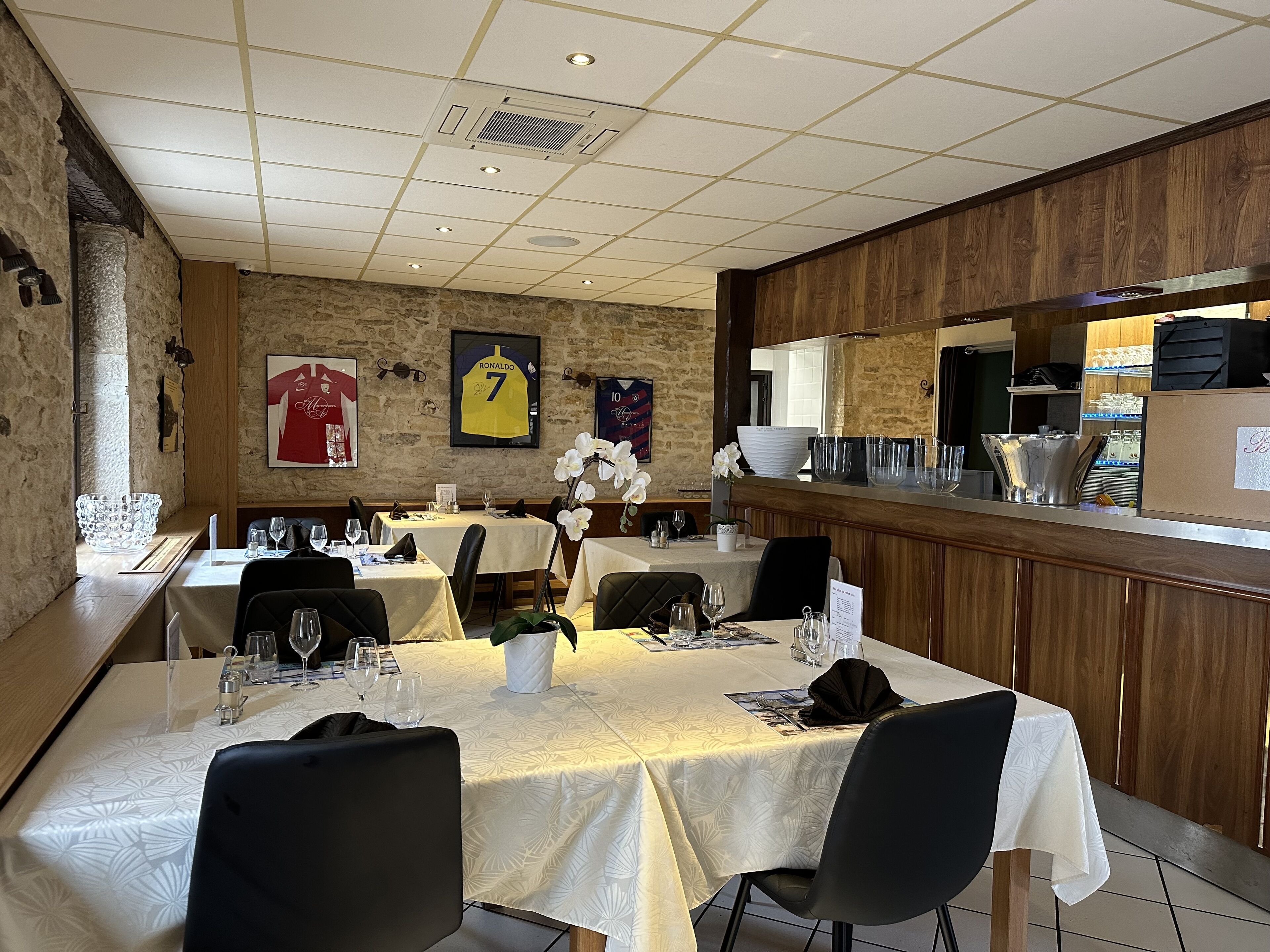 A restaurant with multiple tables, a bar area, and sports jerseys on the wall.
