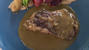 A blue plate with a steak and gravy, accompanied by a side of vegetables and a beetroot slice.