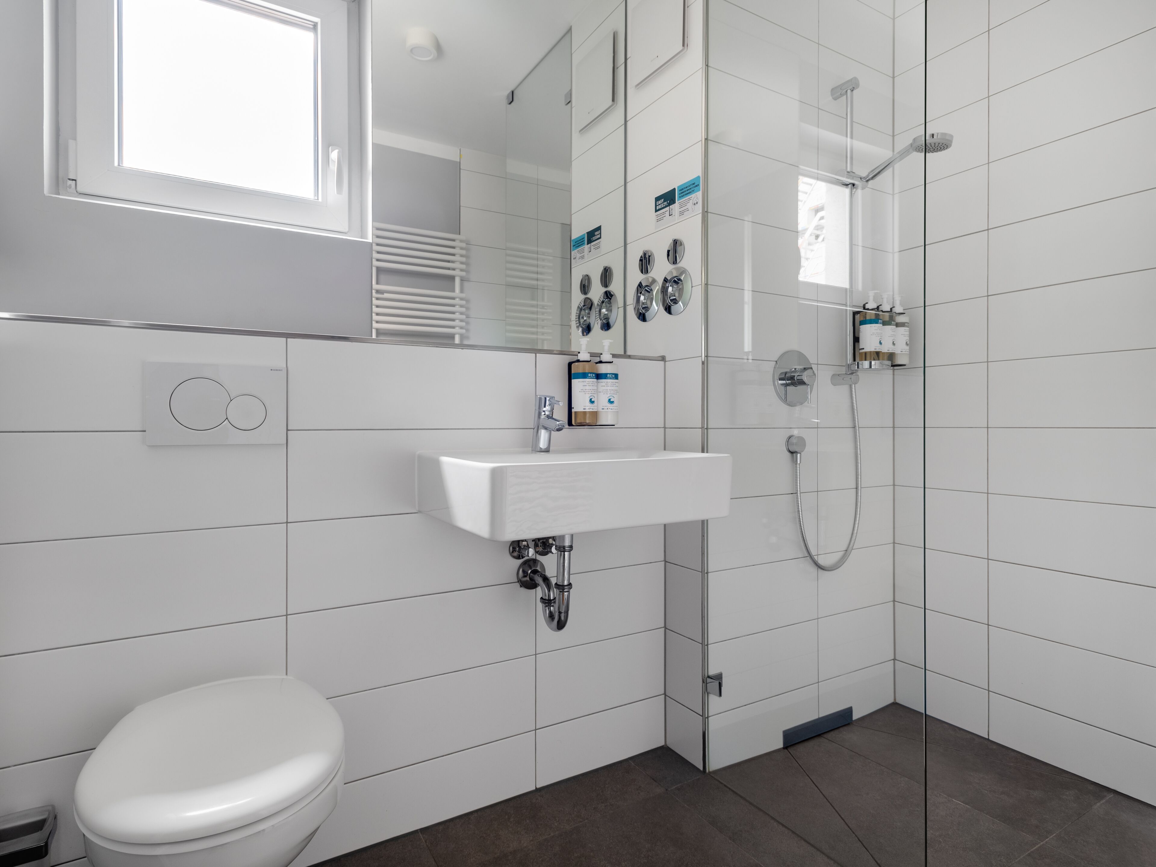 A modern bathroom with a white sink, a toilet, and a shower.