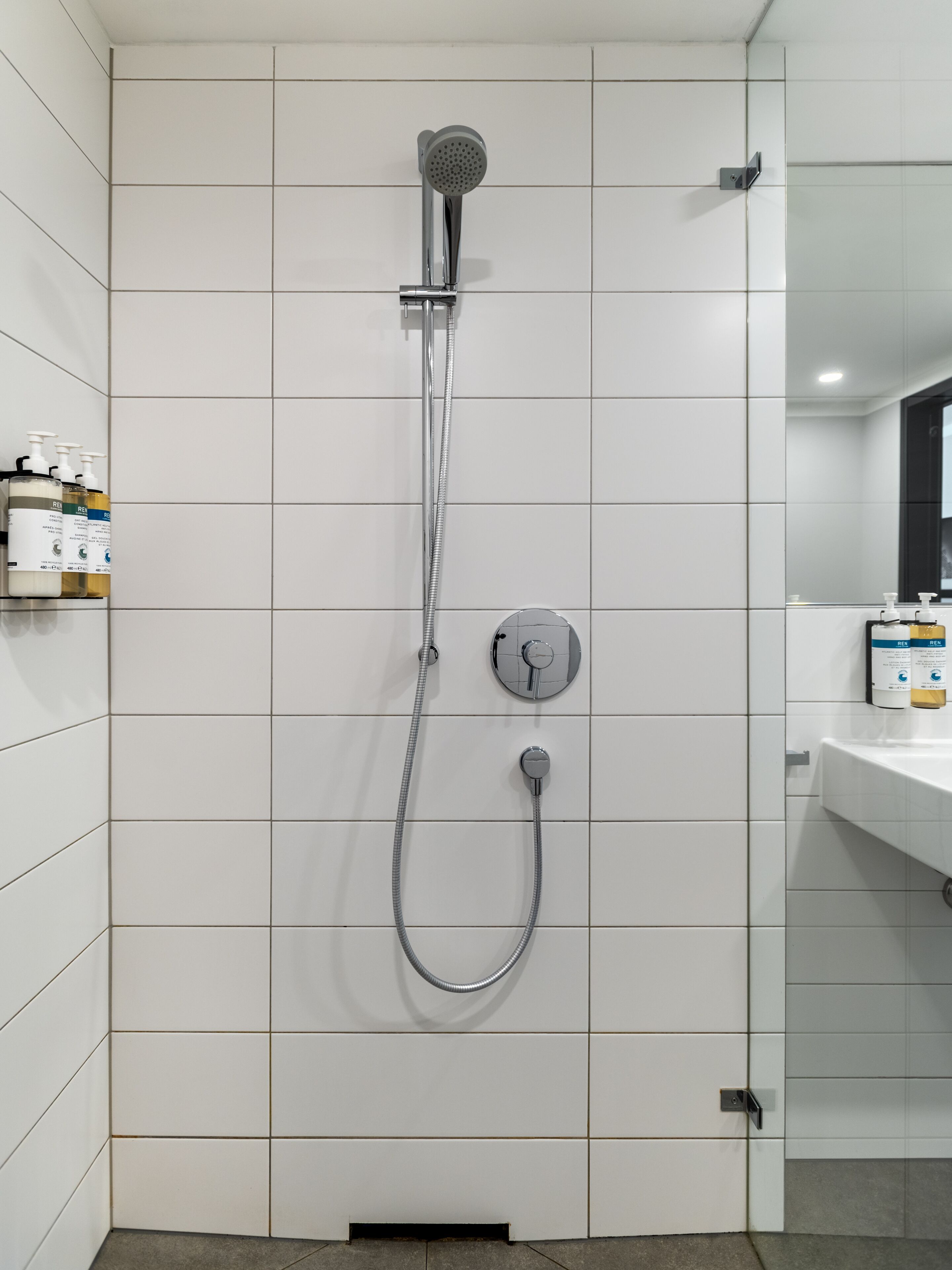A bathroom with a shower, a sink, and toiletries on the wall.