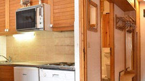 A compact kitchen with a microwave, dishwasher, and stove. - Charming Studio for 4 in Meribel, Near Slopes and Shops (Méribel)