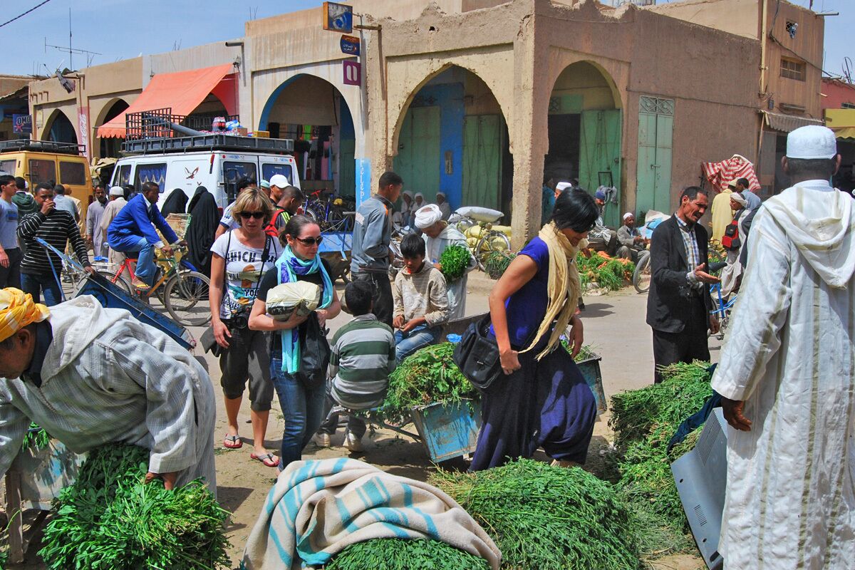 A bustling outdoor market with people shopping and vendors selling goods.