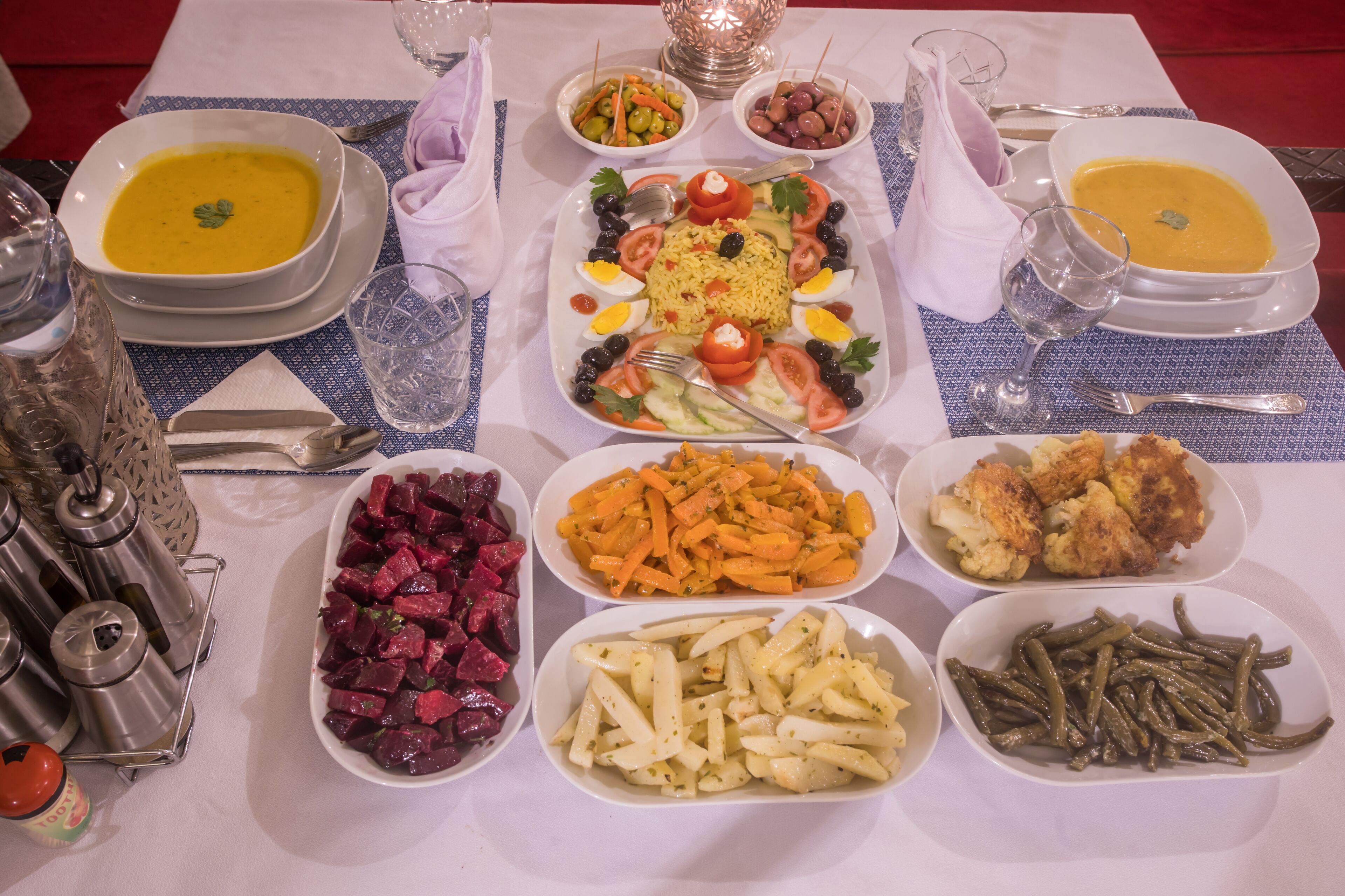 A table set with various dishes including soup, rice, vegetables, and meats.