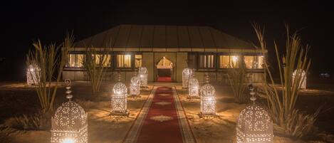 A building with a red carpet leading to a door, surrounded by decorative lanterns.