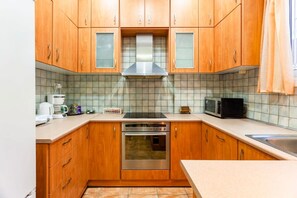 Een keuken met houten kastjes, een roestvrijstalen afzuigkap, een magnetron en een koffiezetapparaat.