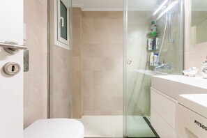 A modern bathroom with a glass shower enclosure, a white sink, and a toilet. - Zografou's Hidden Gem - Athens Charming Home (Zografou)