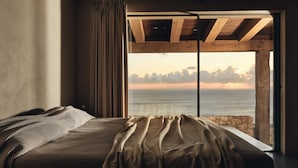 Une chambre avec un grand lit, une vue sur la mer et un plafond en bois.