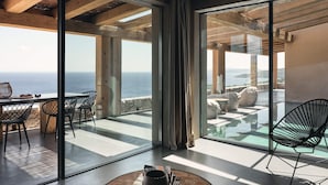 Un intérieur moderne avec de grandes portes vitrées donnant sur une terrasse offrant une vue sur la mer.