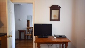 A room with a wooden table, a flat-screen TV, a mirror, and a door leading to another room. - Incredible Location One Bedroom Apartment (Potts Point)