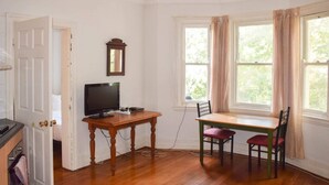 A room with a wooden table, two chairs, a television, and a window with curtains. - Incredible Location One Bedroom Apartment (Potts Point)