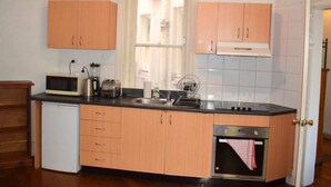 A compact kitchen with wooden cabinets, a microwave, a toaster, a sink, and a built-in oven. - Incredible Location One Bedroom Apartment (Potts Point)