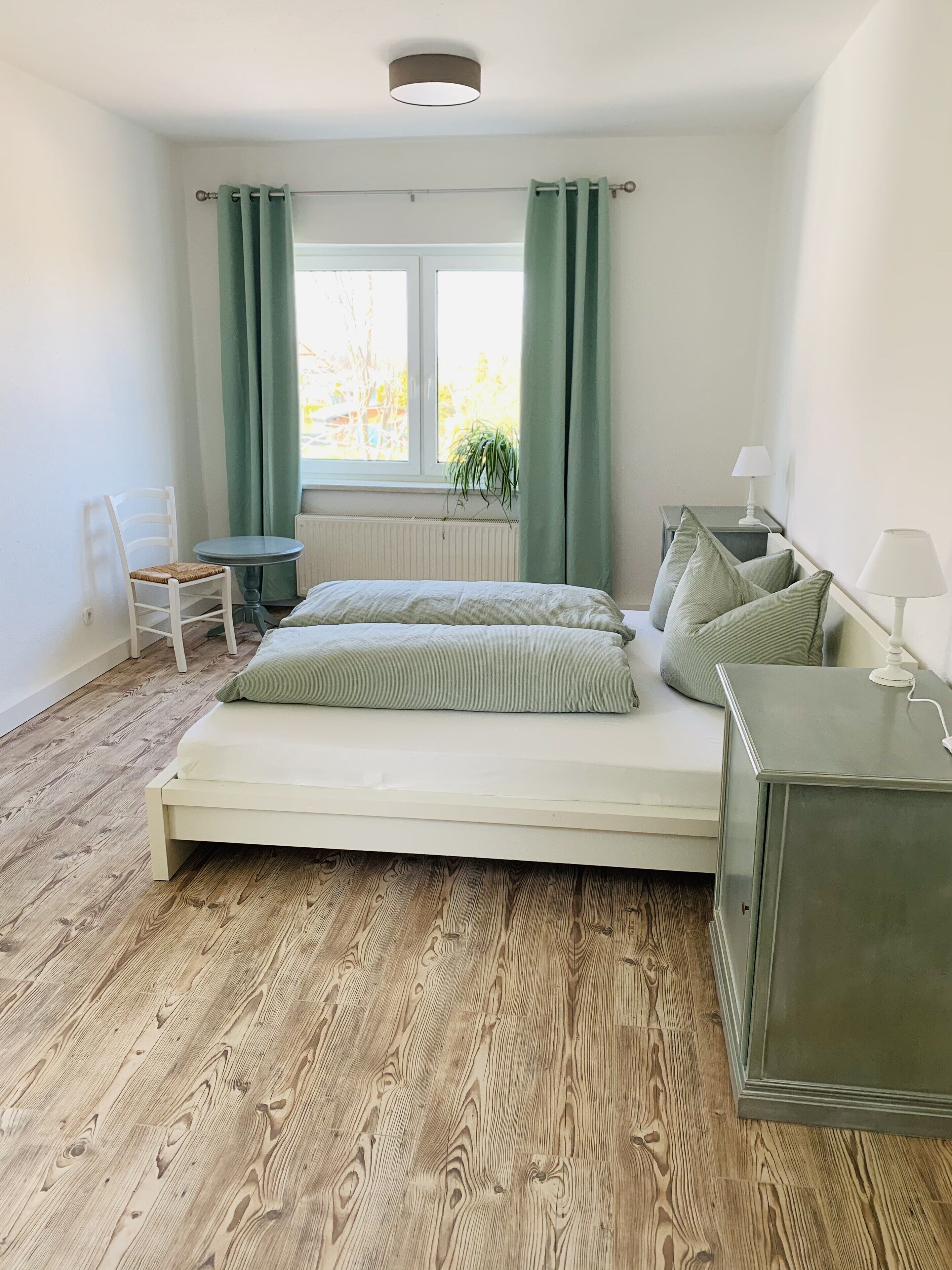 A bedroom with a bed, a chair, a table, and a lamp.