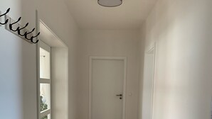 Un couloir doté d’un plancher en bois, de murs blancs et d’une porte au fond.