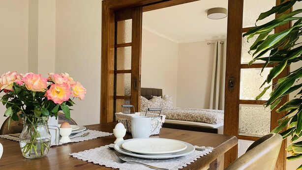 Une table à manger dressée avec des assiettes, un pichet et un vase de fleurs.