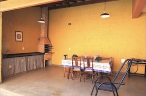A kitchen with a built-in oven, a dining table with chairs, and pendant lights. - Casa Relax Brotas (Brotas)