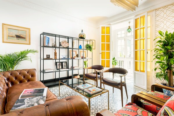 A living room with a leather sofa, a black bookshelf, and a wooden coffee table.