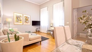 A modern living room with a sofa, a glass coffee table, a flat-screen TV, and two framed artworks on the wall. - Genteel Home Vinuesa (Seville)
