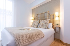 Un dormitorio moderno con una cama grande, dos lámparas fijadas a la pared y un cabecero decorativo.
