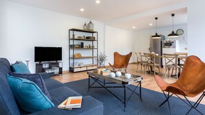 Un salon moderne avec un canapé, une table basse et un téléviseur. Il y a également un coin repas avec des chaises et une table.