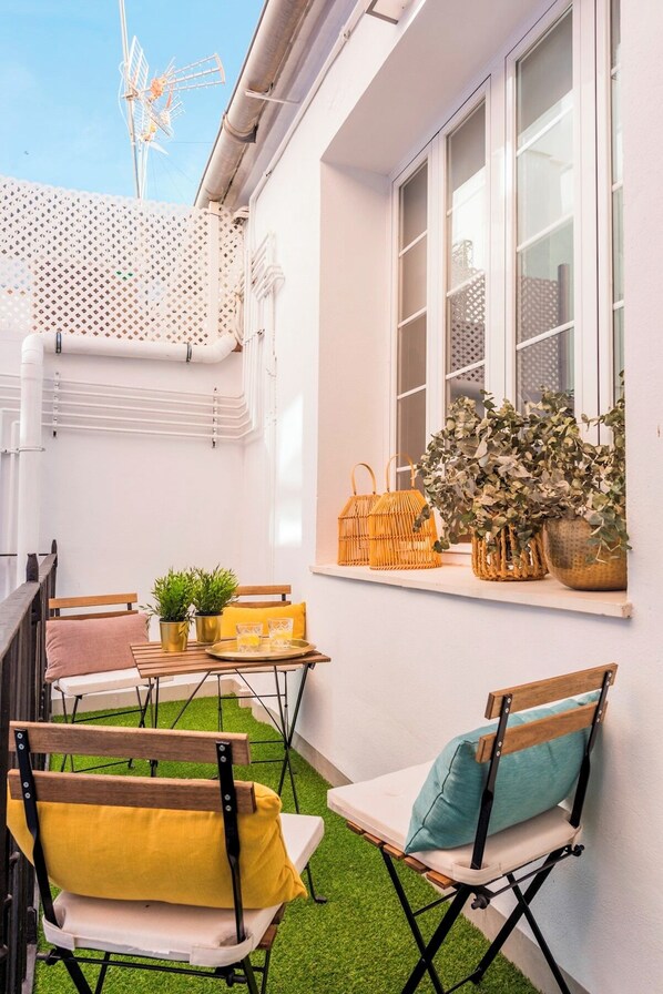 A small outdoor seating area with a table, chairs, and potted plants.