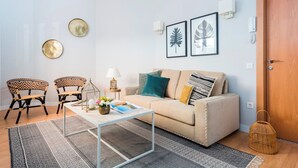 A living room with a beige sofa, two patterned chairs, a coffee table, and a door.