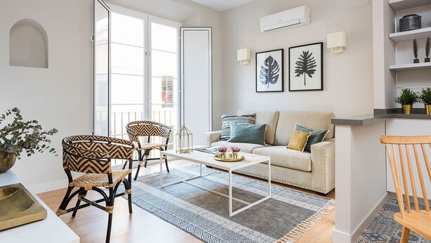 A modern living room with a sofa, two armchairs, a coffee table, and a dining table. There are two framed leaf artworks on the wall, and a small potted plant on the side table. - Genteel Home Trinidad Grund G (Málaga)