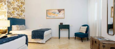 Une chambre avec deux lits, un bureau, une chaise, une commode, un tableau et un miroir.