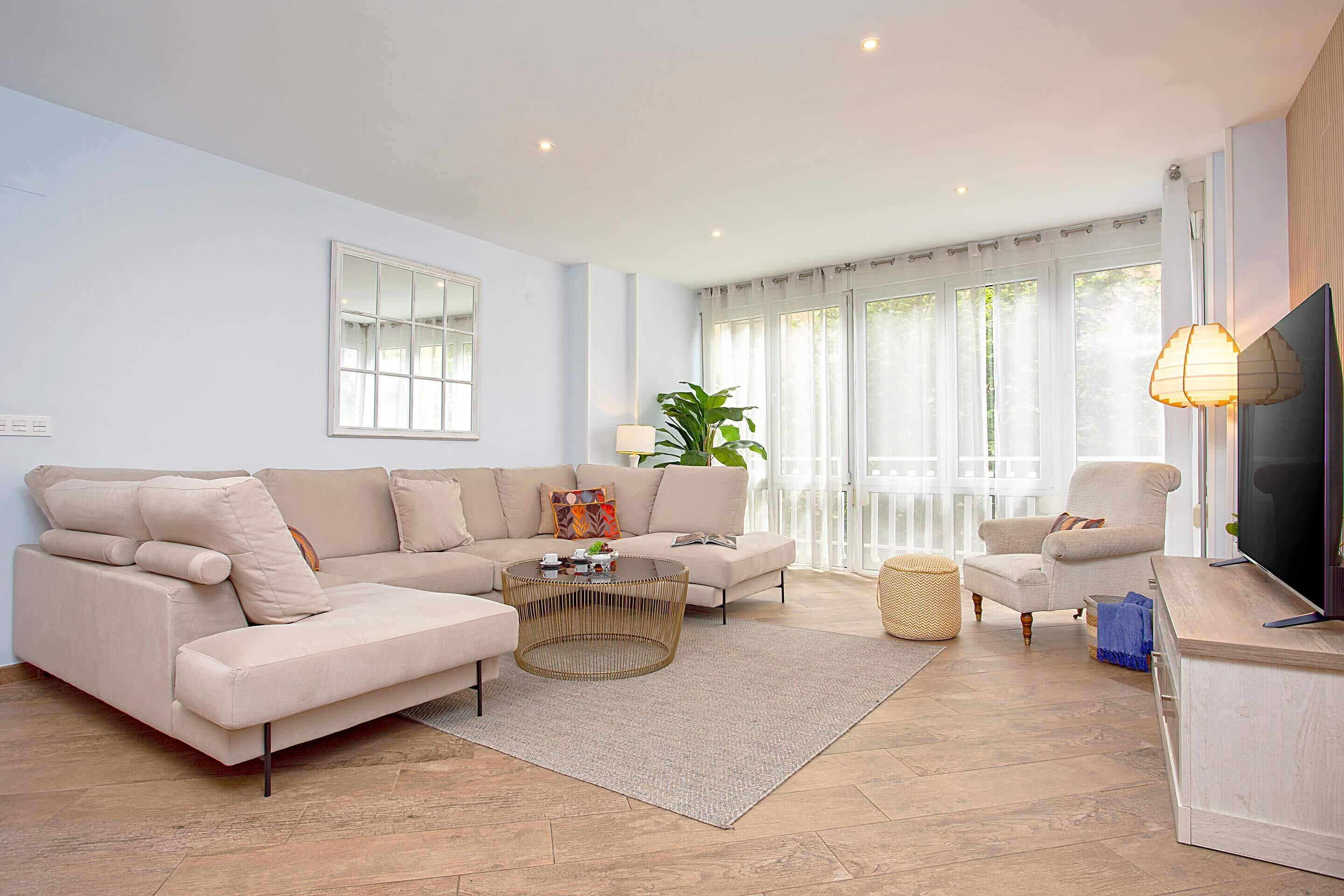 Ein modernes Wohnzimmer mit einem beigefarbenen Sofa, einem runden Couchtisch und einem Fernsehschrank.