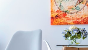 A modern room with a white chair, a glass table, and a magazine on the chair. - Genteel Home Albareda II (Seville)