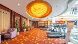 A hotel lobby with a red carpet, exercise equipment, and a large circular light fixture. - Montriche International Hotel (WEIFANG)