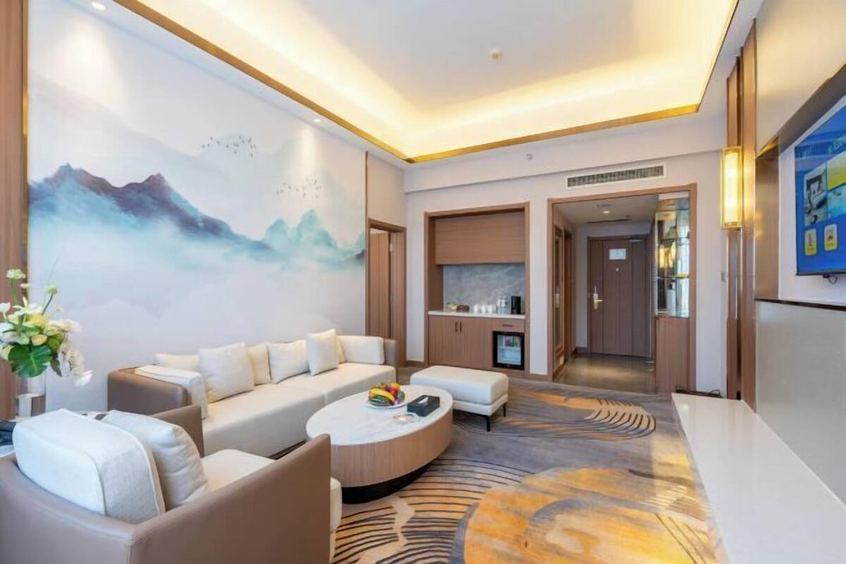 Un hall d’hôtel moderne avec un ensemble de canapés, une table basse ronde, un tapis décoratif et un grand tableau mural.