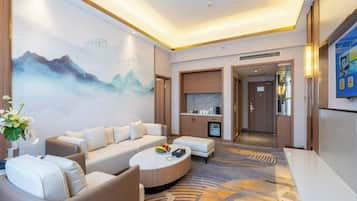 A modern hotel lobby with a sofa set, a round coffee table, a decorative rug, and a large wall painting.