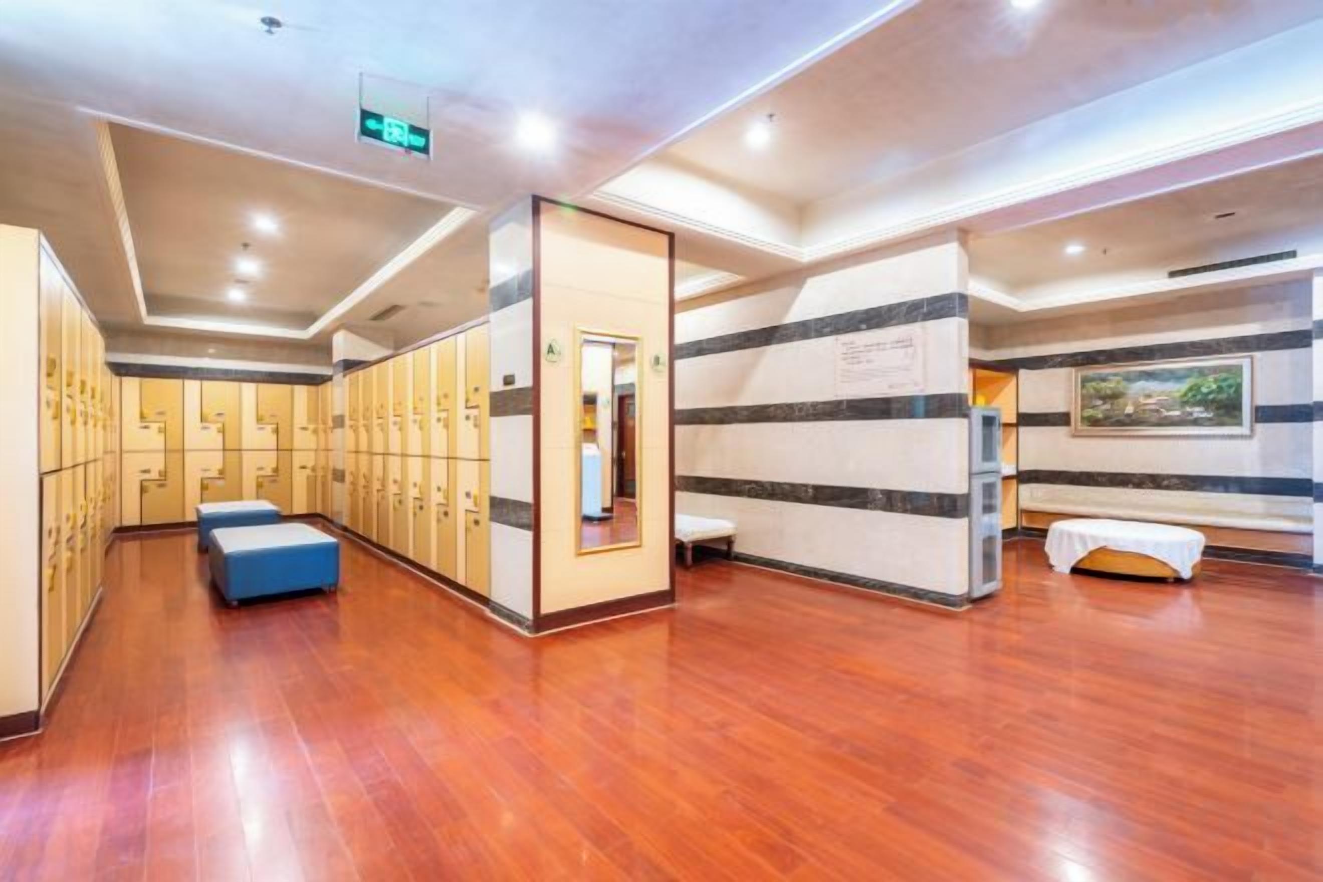 A hotel lobby with wooden flooring, a seating area, and a row of lockers.